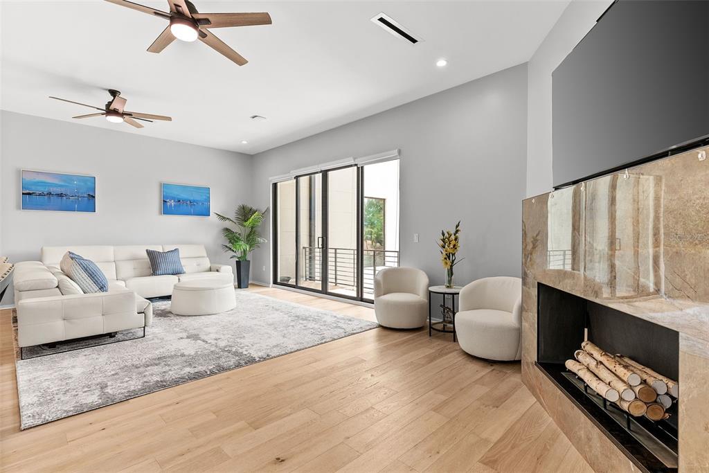 A modern living room features a white sectional, fireplace, and sliding glass doors to a balcony — 92 W DAVIS BOULEVARD, TAMPA, FL