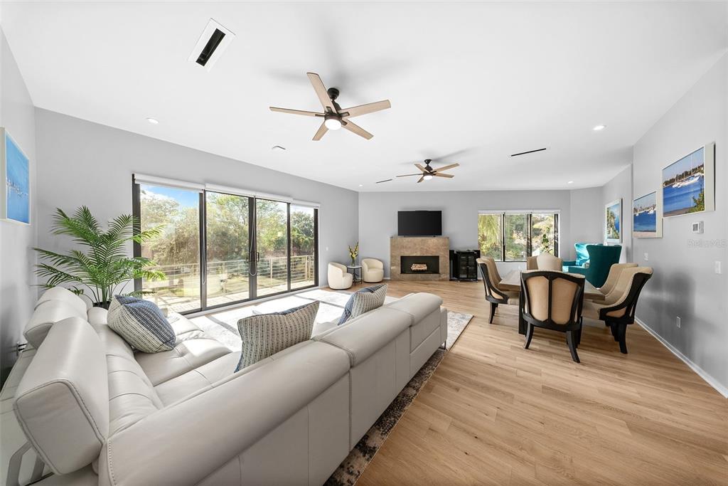 A spacious open-concept living and dining area with light wood floors and a stone fireplace — 92 W DAVIS BOULEVARD, TAMPA, FL