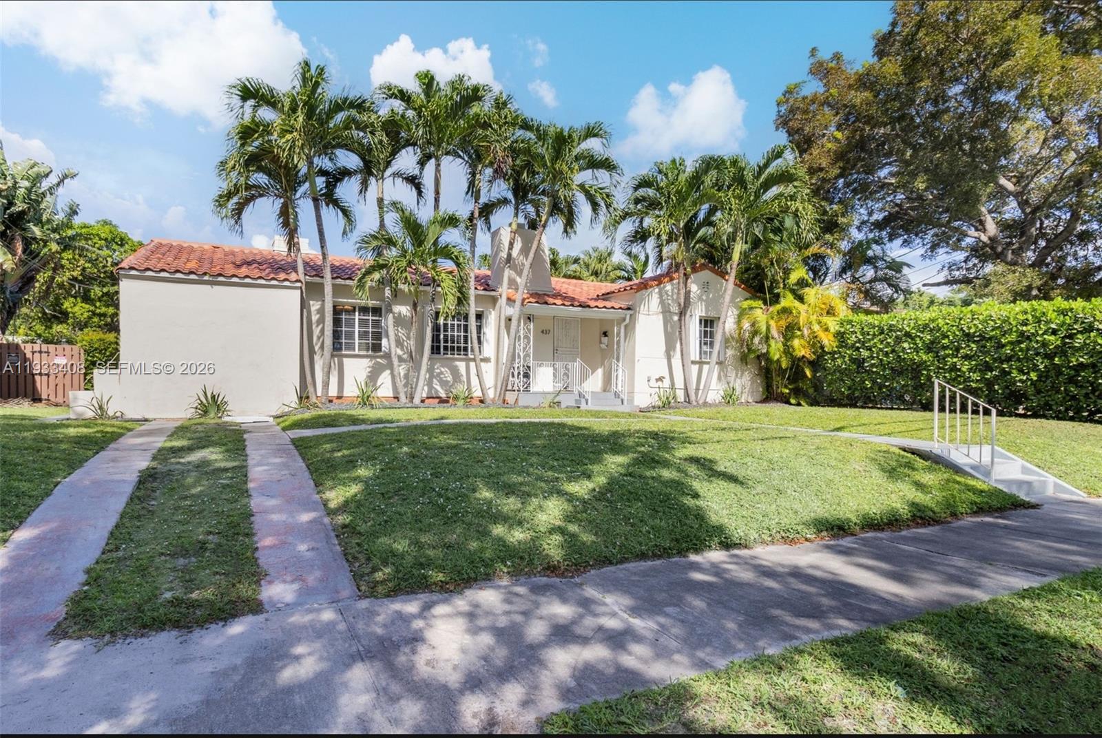 A single-story house with a red tile roof and palm trees sits behind a lawn — 437 NE 107th St, Miami FL 33161, MIAMI, FL