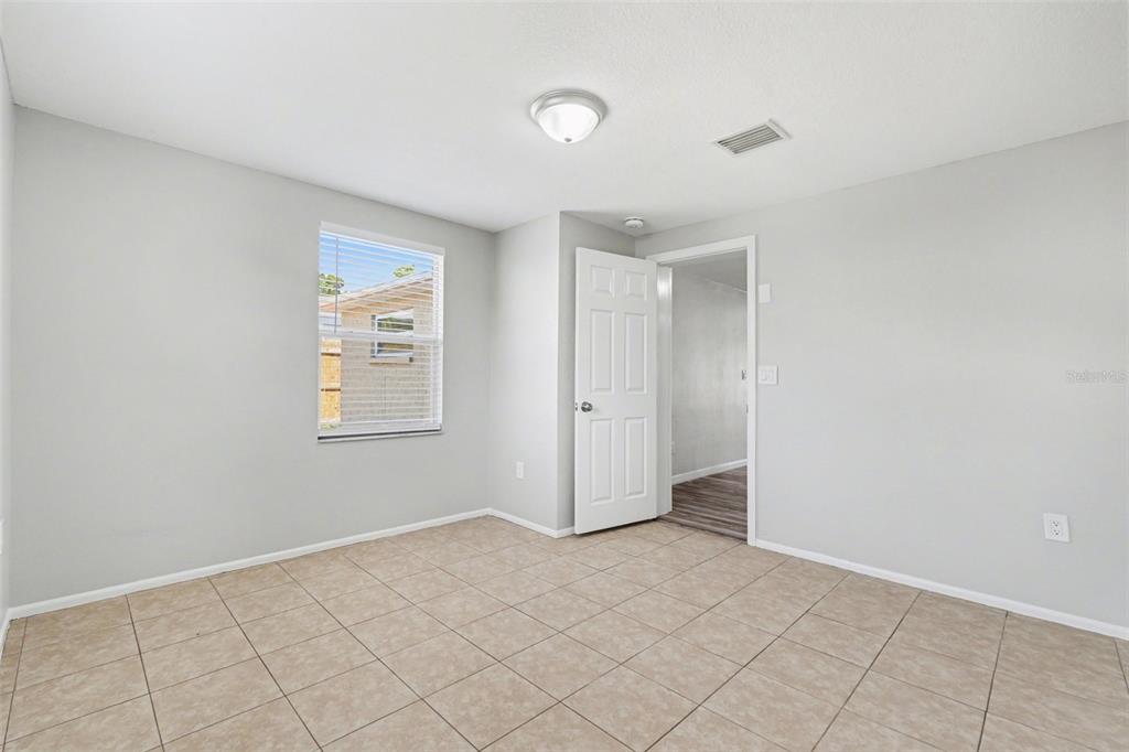 A room with light gray walls, beige tile flooring, a window, and an open doorway — 6337 BONAIRE AVENUE, NEW PORT RICHEY, FL