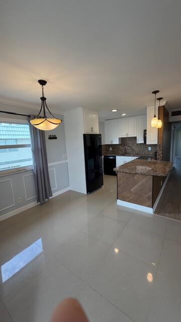 A kitchen features white cabinetry, a granite island, black appliances, and light-colored tile flooring — 276 Monaco F, Delray Beach FL 33446, DELRAY BEACH, FL