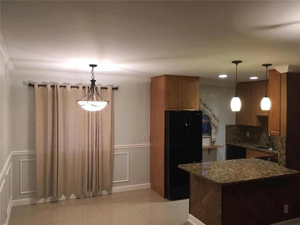 A dining area with a chandelier next to a kitchen featuring wood cabinets and granite countertops — 276 Monaco F, Delray Beach FL 33446, DELRAY BEACH, FL