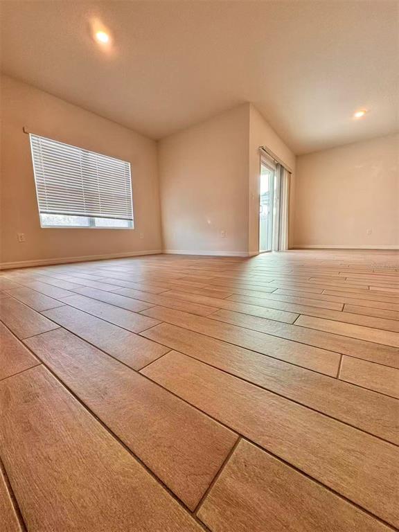 An empty room features light wood-look tile flooring, white walls, and a sliding glass door — 8244 SW 60TH ROAD, GAINESVILLE, FL
