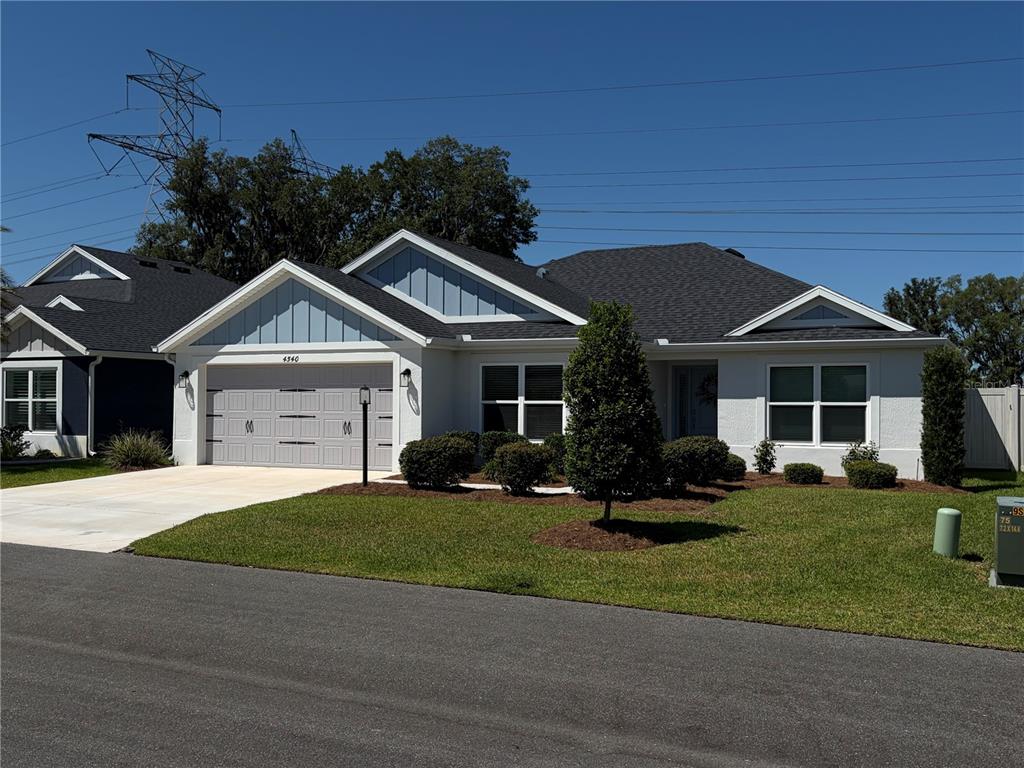 A single-story house with a gray garage, white exterior, and blue gable accents — 4540 BROOKE LANE, THE VILLAGES, FL
