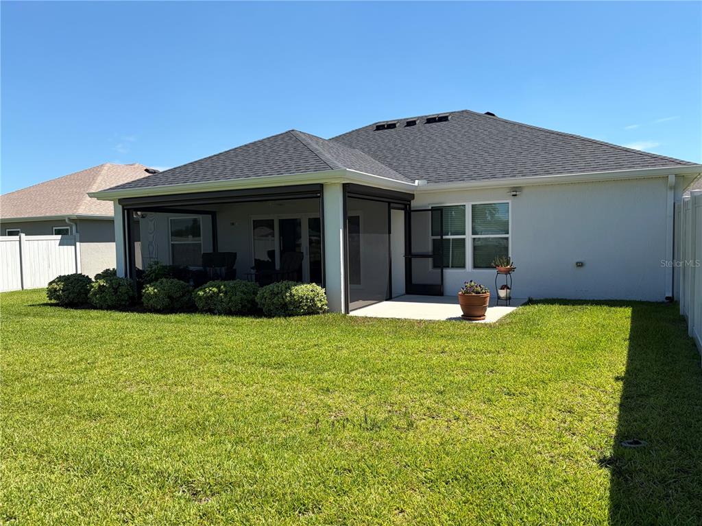 The backyard features a screened-in patio, a concrete slab, and a manicured lawn — 4540 BROOKE LANE, THE VILLAGES, FL