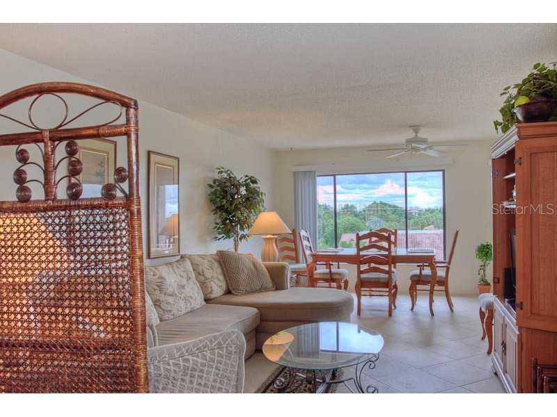 A living room with a sectional sofa, glass coffee table, and dining area near a window — 131 GARFIELD DRIVE UNIT 4C, SARASOTA, FL