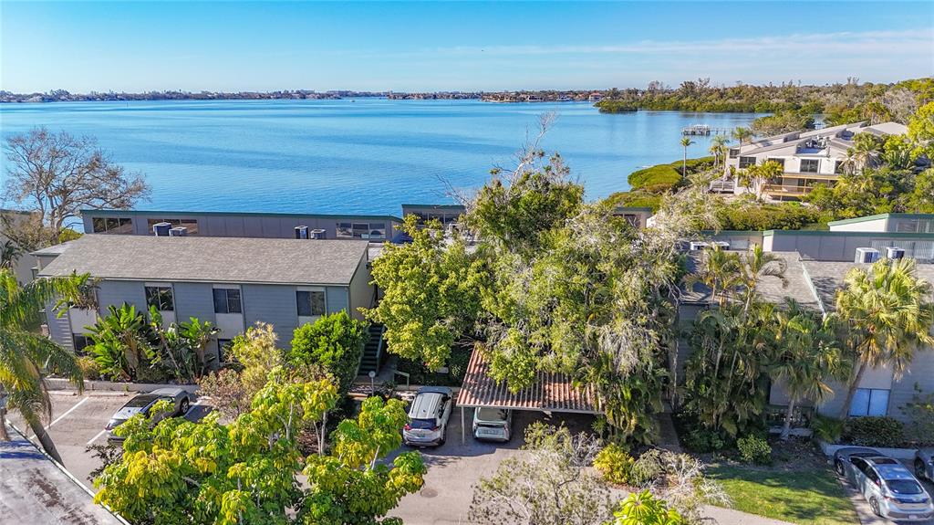 An aerial view shows a multi-story apartment complex with a parking lot and waterfront access — 1511 PELICAN POINT DRIVE UNIT BA180, SARASOTA, FL