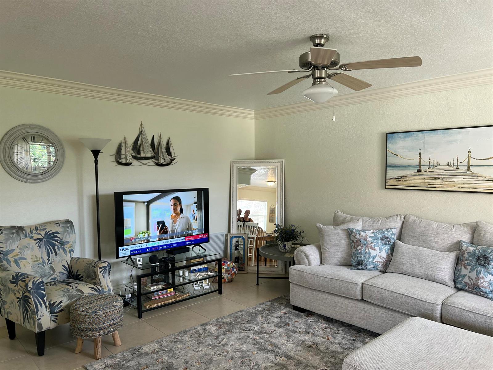 A living room features a light-colored sofa, patterned armchair, television on a stand, and ceiling fan — 84 Saxony B, Delray Beach FL 33446, DELRAY BEACH, FL