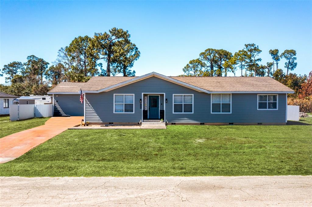 A single-story house with blue horizontal siding, a brown roof, and a front lawn — 323 GREENWOOD AVENUE, LEHIGH ACRES, FL