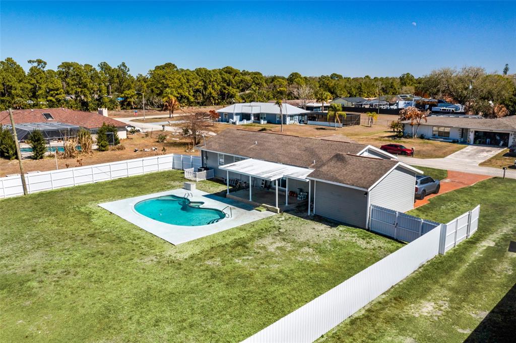 An aerial view of a house with a backyard pool and a white vinyl fence — 323 GREENWOOD AVENUE, LEHIGH ACRES, FL
