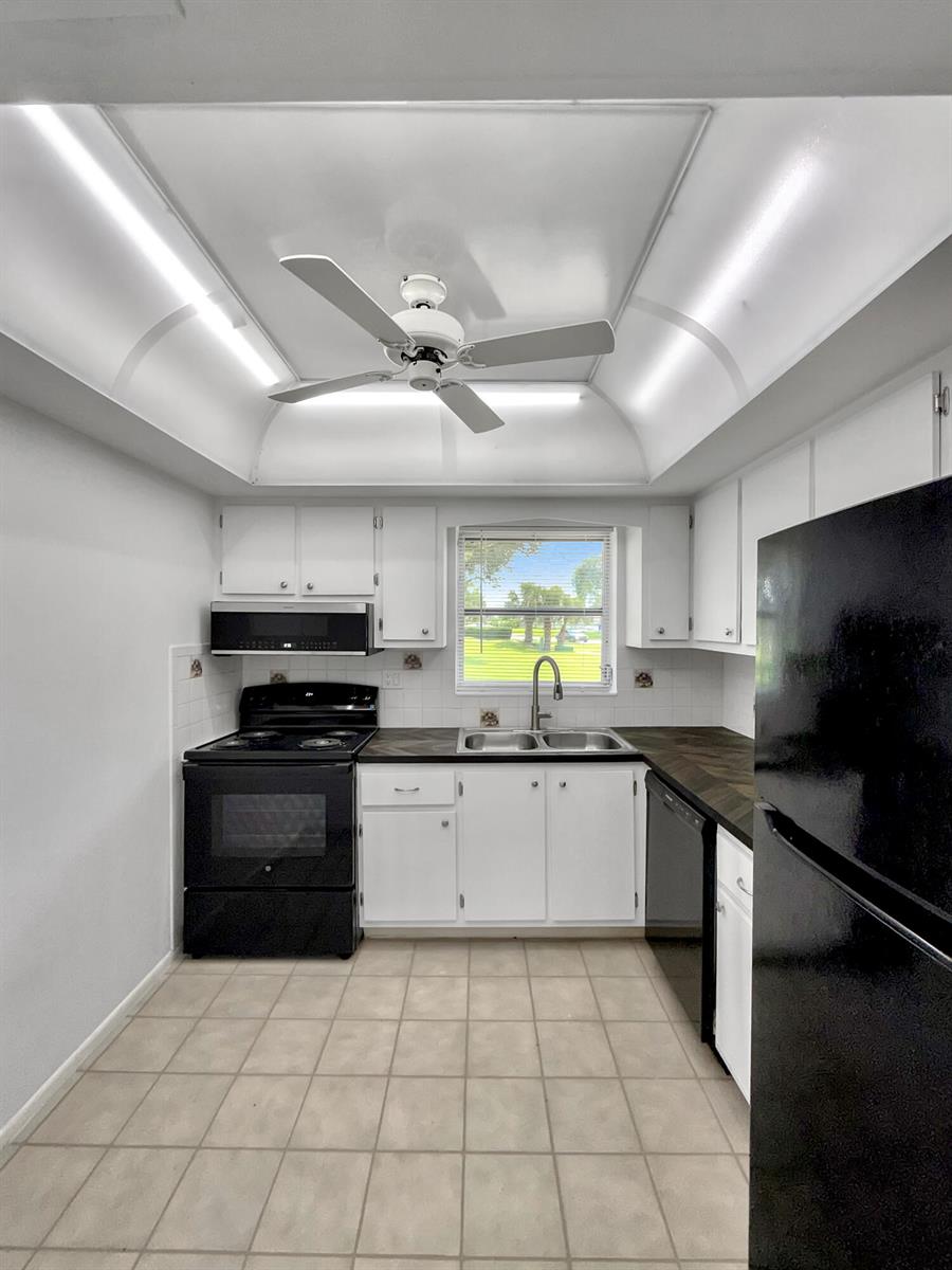 A kitchen features white cabinets, black appliances, dark countertops, and a ceiling fan — 5263 Cresthaven Boulevard # A, West Palm Beach FL 33415, WEST PALM BEACH, FL