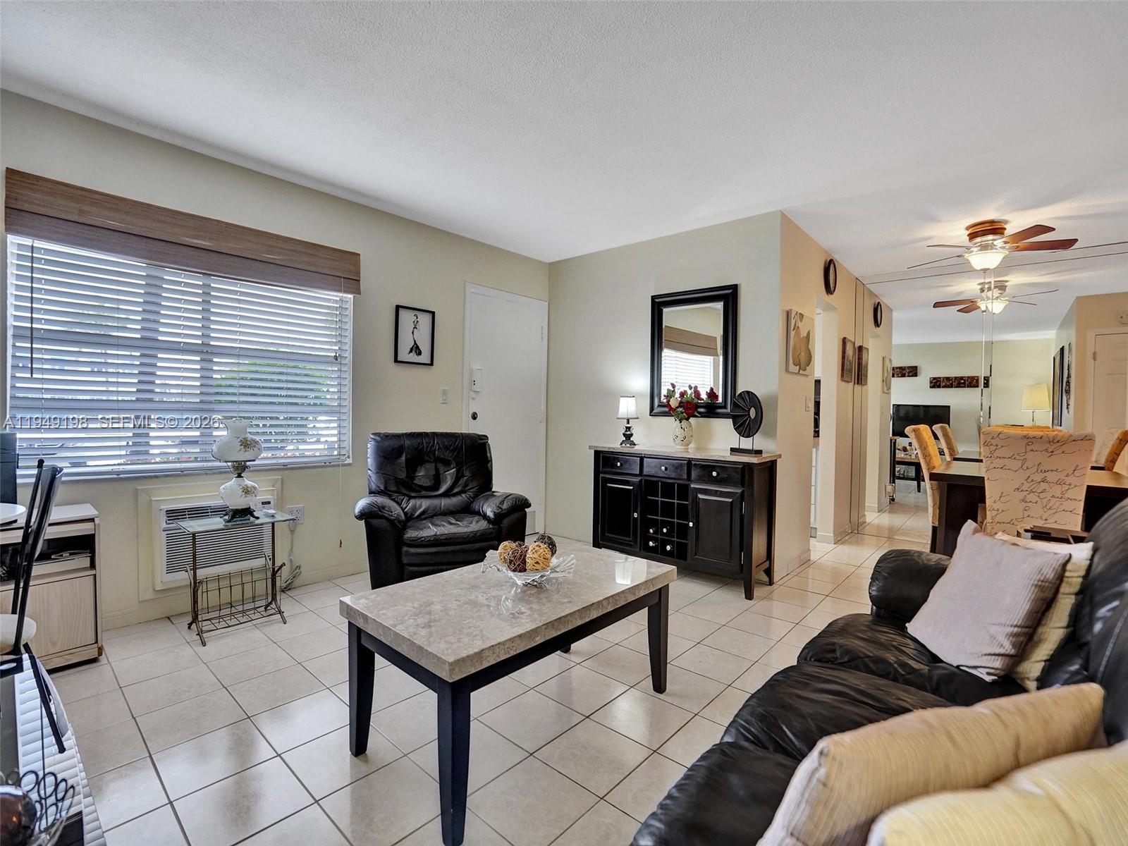 A living room with tile floors, a black leather armchair, and a marble-topped coffee table — 16901 NE 13th Ave # 110, Miami FL 33162, MIAMI, FL
