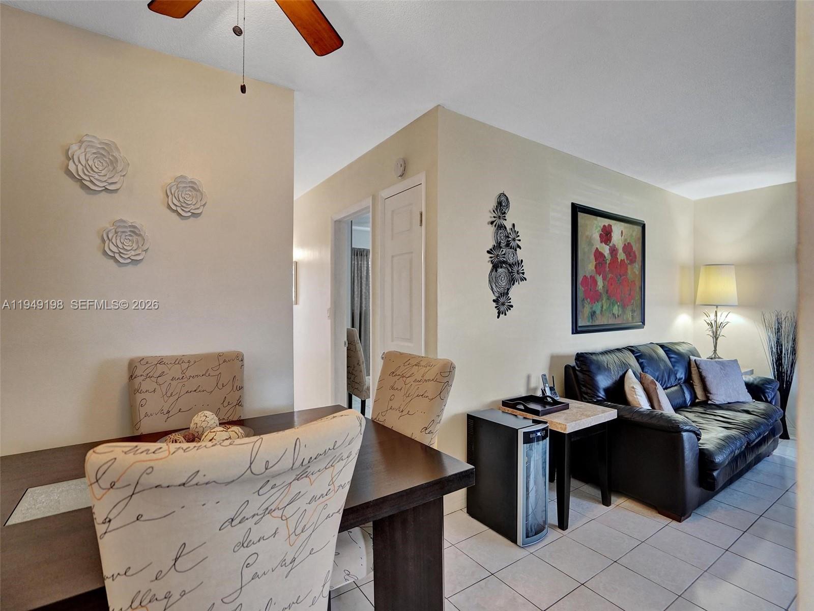 A dining area with patterned chairs sits adjacent to a living room with a leather sofa — 16901 NE 13th Ave # 110, Miami FL 33162, MIAMI, FL