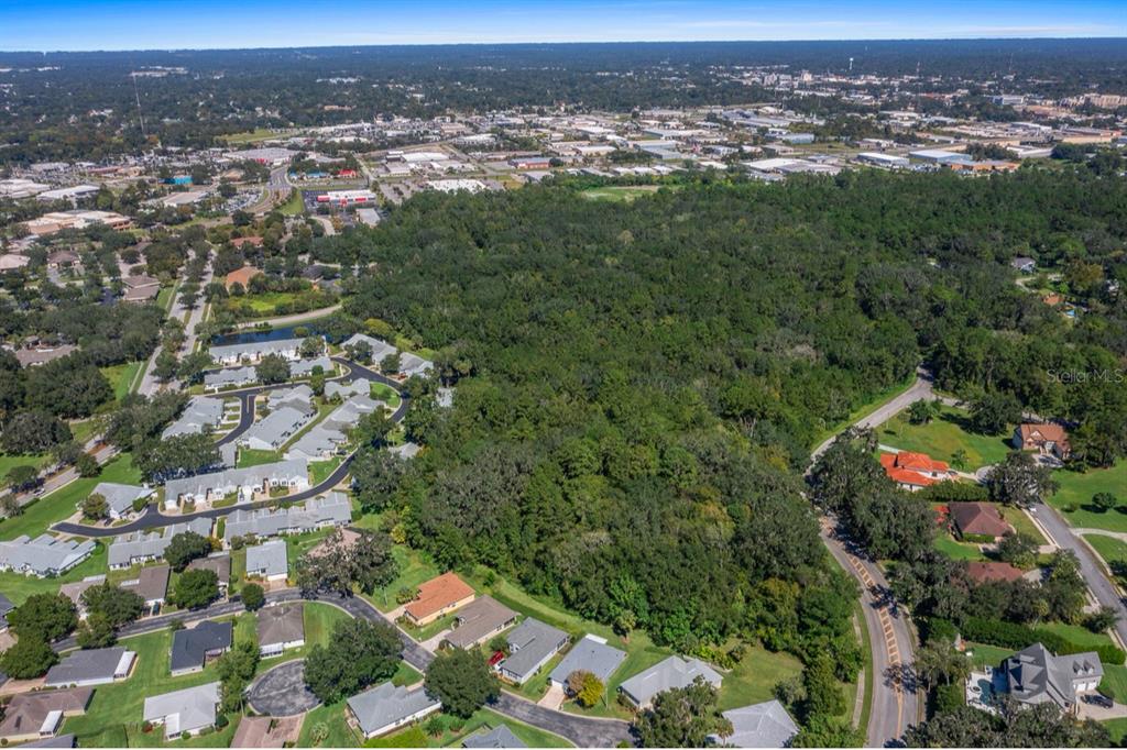 An aerial view shows a large wooded lot surrounded by residential neighborhoods and commercial buildings — TBD SW 20TH PLACE, OCALA, FL