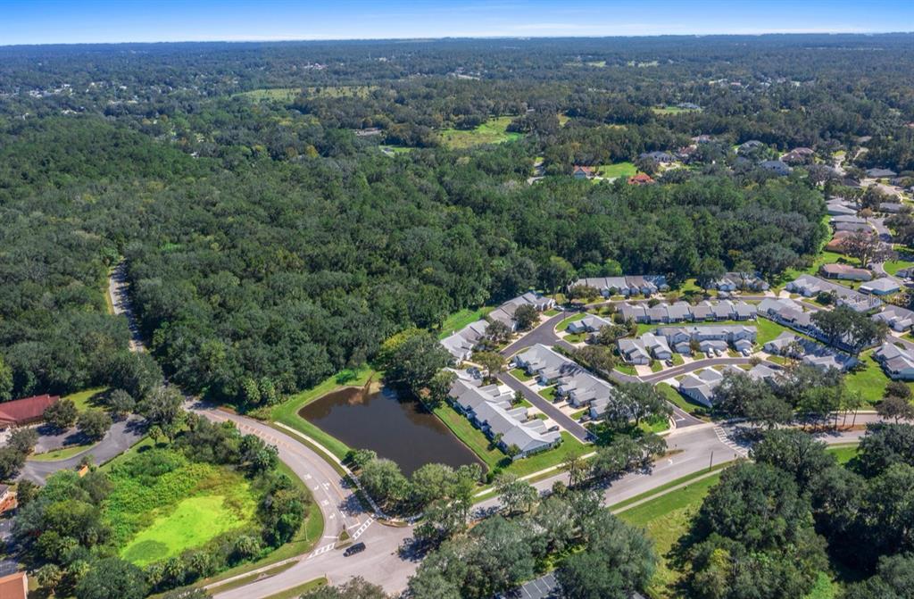 An aerial view shows a residential neighborhood with townhomes, a retention pond, and surrounding woods — TBD SW 20TH PLACE, OCALA, FL