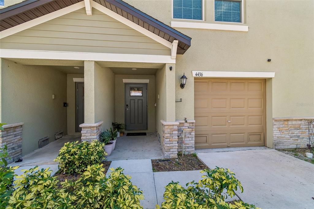 A row of three-story townhomes with beige stucco siding, attached garages, and concrete driveways — 4436 TUSCAN LOON DRIVE, TAMPA, FL