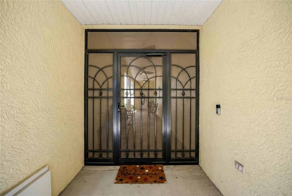A covered entryway features a decorative black metal security door and a welcome mat — 8037 SW 81ST LOOP, OCALA, FL