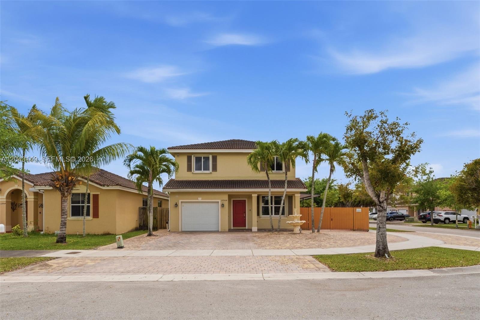 A two-story suburban house with a red front door, a garage, and palm trees — 12964 SW 285th Ter, Homestead FL 33033, HOMESTEAD, FL