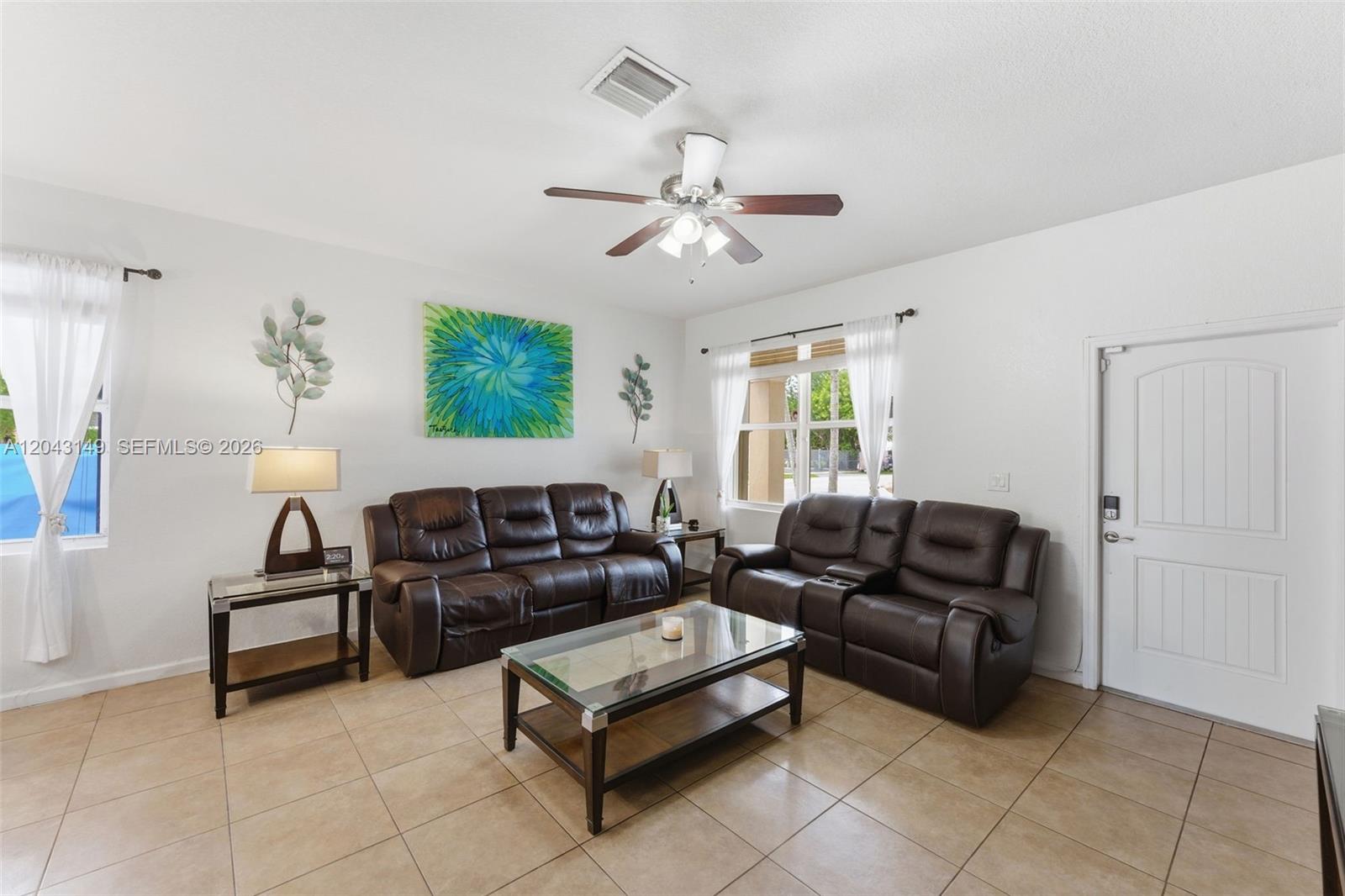 A living room features two brown leather sofas, a glass coffee table, and tile flooring — 12964 SW 285th Ter, Homestead FL 33033, HOMESTEAD, FL