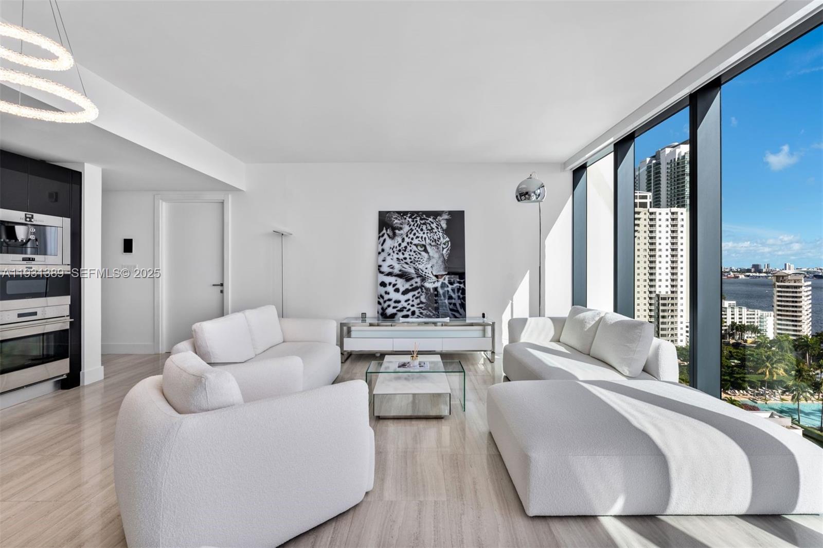A modern living room features white furniture, a large leopard print, and floor-to-ceiling windows — 1451 Brickell Ave # 1803, Miami FL 33131, MIAMI, FL