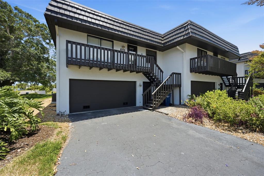 A two-story building features white stucco walls, dark brown trim, balconies, and ground-level garages — 10301 WATERBIRD WAY UNIT 39, BRADENTON, FL