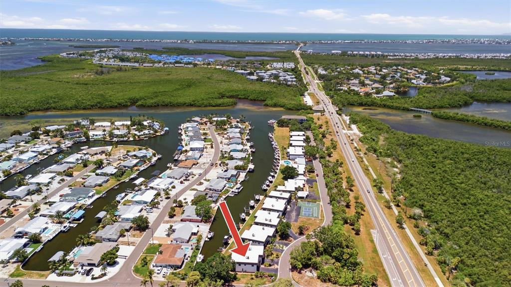 An aerial view shows a residential waterfront community with a red arrow pointing to a building — 10301 WATERBIRD WAY UNIT 39, BRADENTON, FL