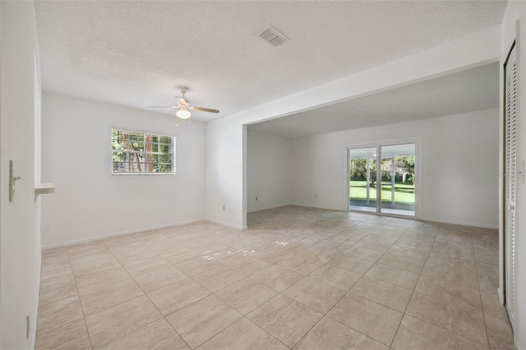 An empty room with light-colored tile flooring, a ceiling fan, and sliding glass patio doors — 498 GREEN SPRING CIR, WINTER SPRINGS, FL