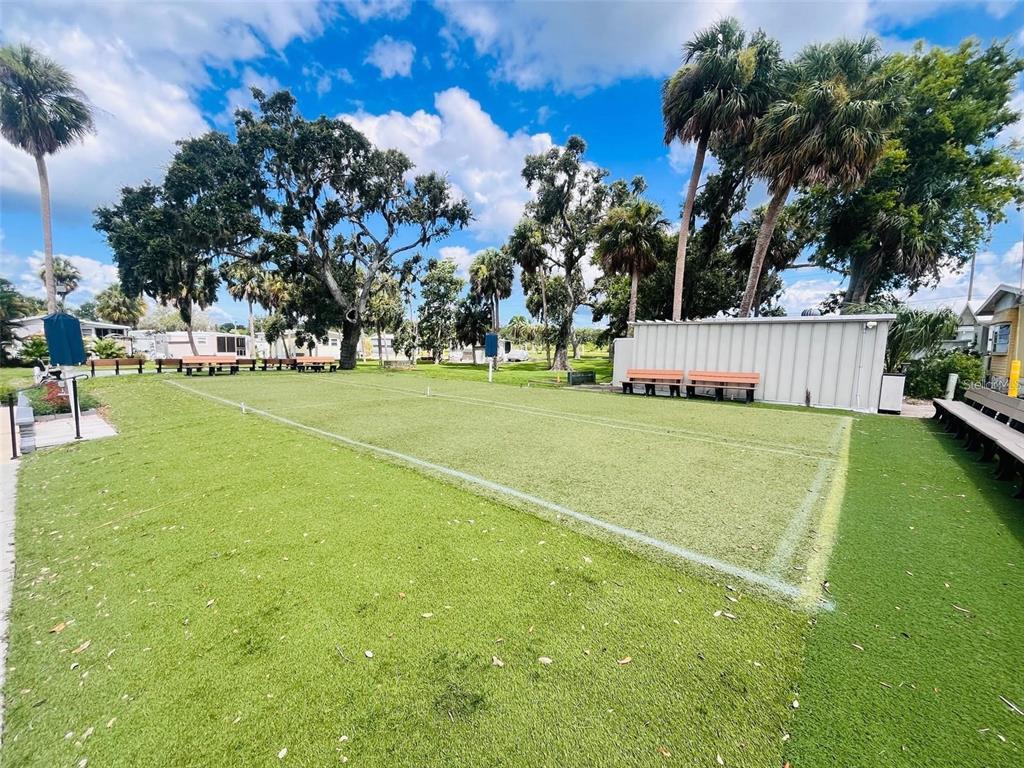 An outdoor bocce ball court with artificial turf sits in a park-like setting with trees — 2215 73RD STREET E UNIT 348, PALMETTO, FL
