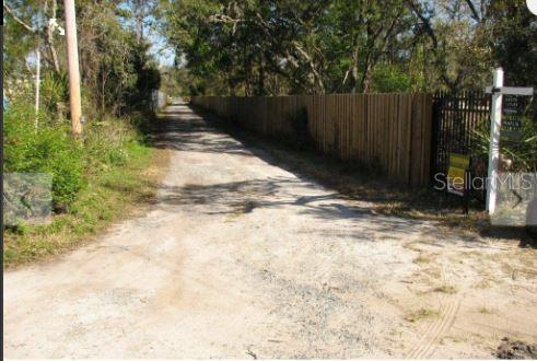 A dirt driveway leads past a wooden fence toward trees on a sunny day — 1349 N FORT CHRISTMAS ROAD, CHRISTMAS, FL