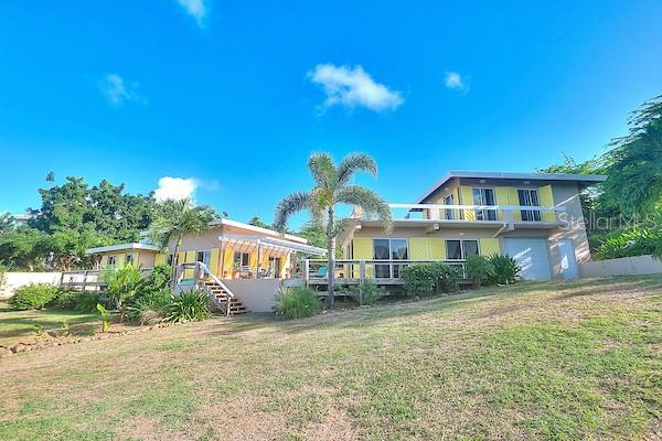 A two-story house with yellow siding, a wooden deck, and a palm tree in front — 16 ALTURAS DE ZONI, CULEBRA, PR