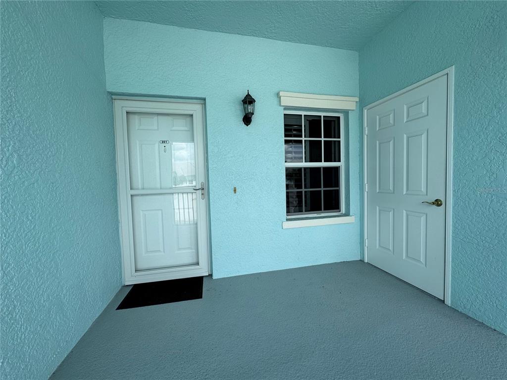 A light blue exterior entryway features a white front door, a storage door, and a window — 5751 SABAL TRACE DRIVE UNIT 201, NORTH PORT, FL