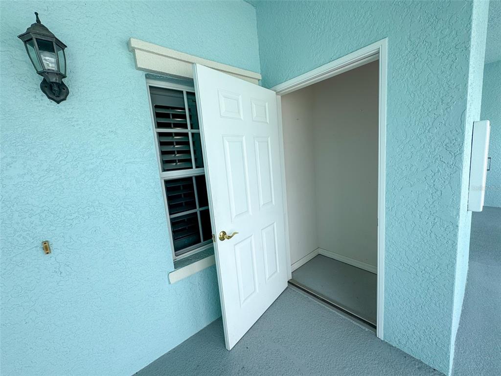 An open white door leads into a small storage closet next to a window — 5751 SABAL TRACE DRIVE UNIT 201, NORTH PORT, FL