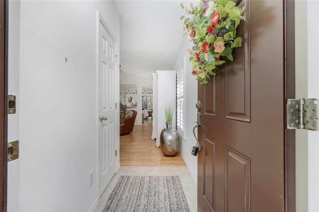 An open brown front door reveals a tiled entryway leading into a hardwood-floored living area — 13136 SW PEMBROKE CIRCLE N, LAKE SUZY, FL