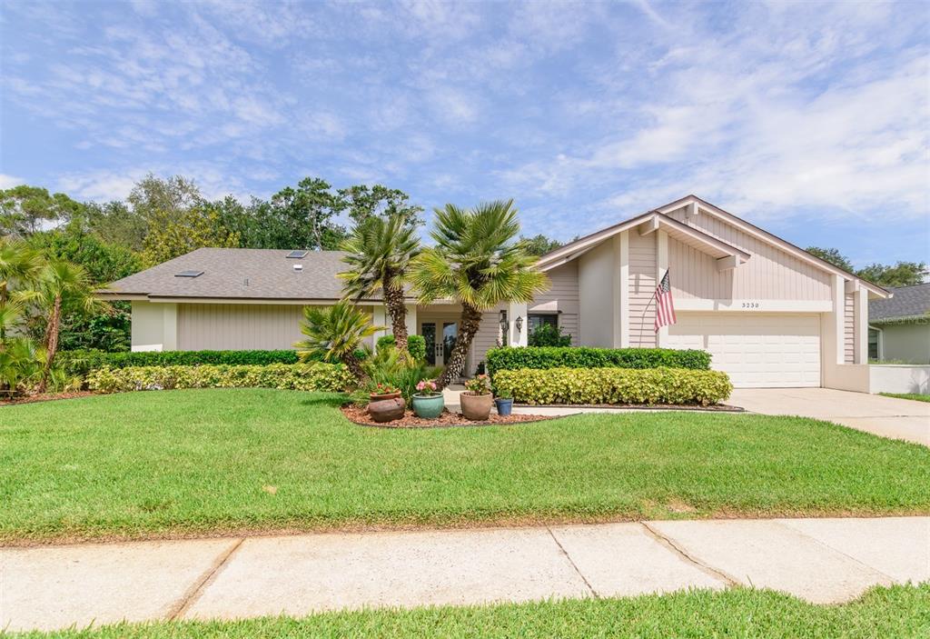 A single-story house with a beige exterior, a two-car garage, and palm trees in front — 3230 SANDY RIDGE DRIVE, CLEARWATER, FL