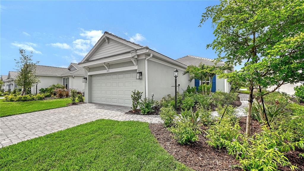 A single-story house with a gray stucco exterior, a paved driveway, and a landscaped front yard — 3231 ALBA CIRCLE, BRADENTON, FL