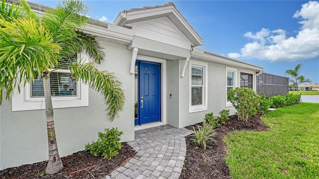 The exterior of a light-colored house features a bright blue front door and a palm tree — 3231 ALBA CIRCLE, BRADENTON, FL
