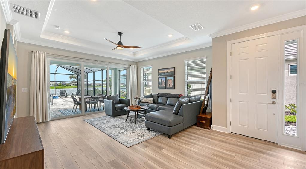 A living room with light wood floors, a sectional sofa, and sliding doors to a patio — 3231 ALBA CIRCLE, BRADENTON, FL