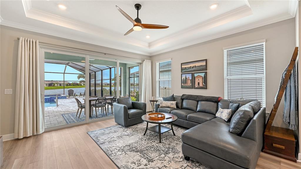 A living room features a gray sectional, an armchair, a ceiling fan, and sliding glass doors — 3231 ALBA CIRCLE, BRADENTON, FL
