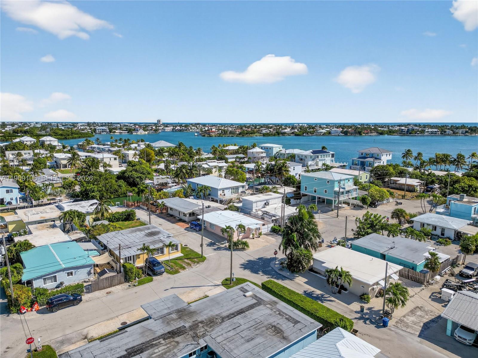 An aerial view shows a coastal neighborhood with houses, palm trees, and a nearby bay — 11405 3rd Avenue Ocean, Marathon FL 33050, MARATHON, FL