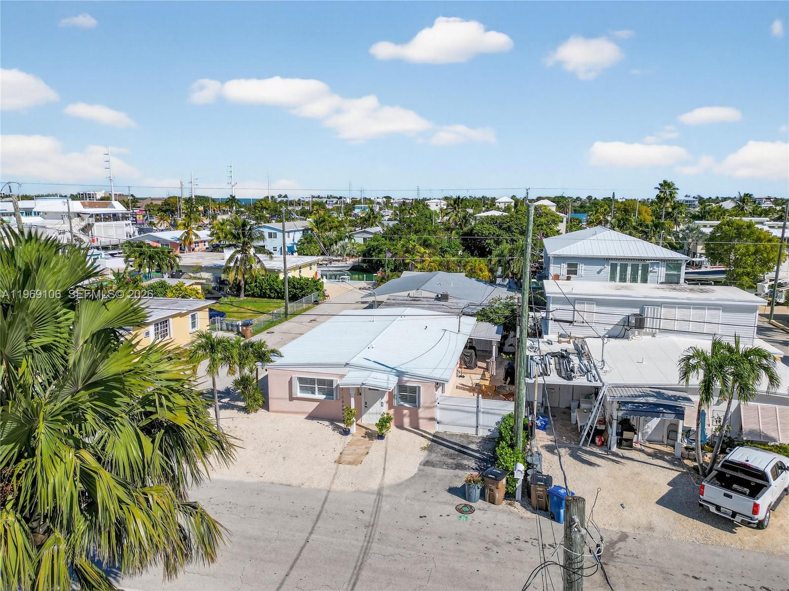 An aerial view shows a pink house with a metal roof and surrounding neighborhood properties — 11405 3rd Avenue Ocean, Marathon FL 33050, MARATHON, FL