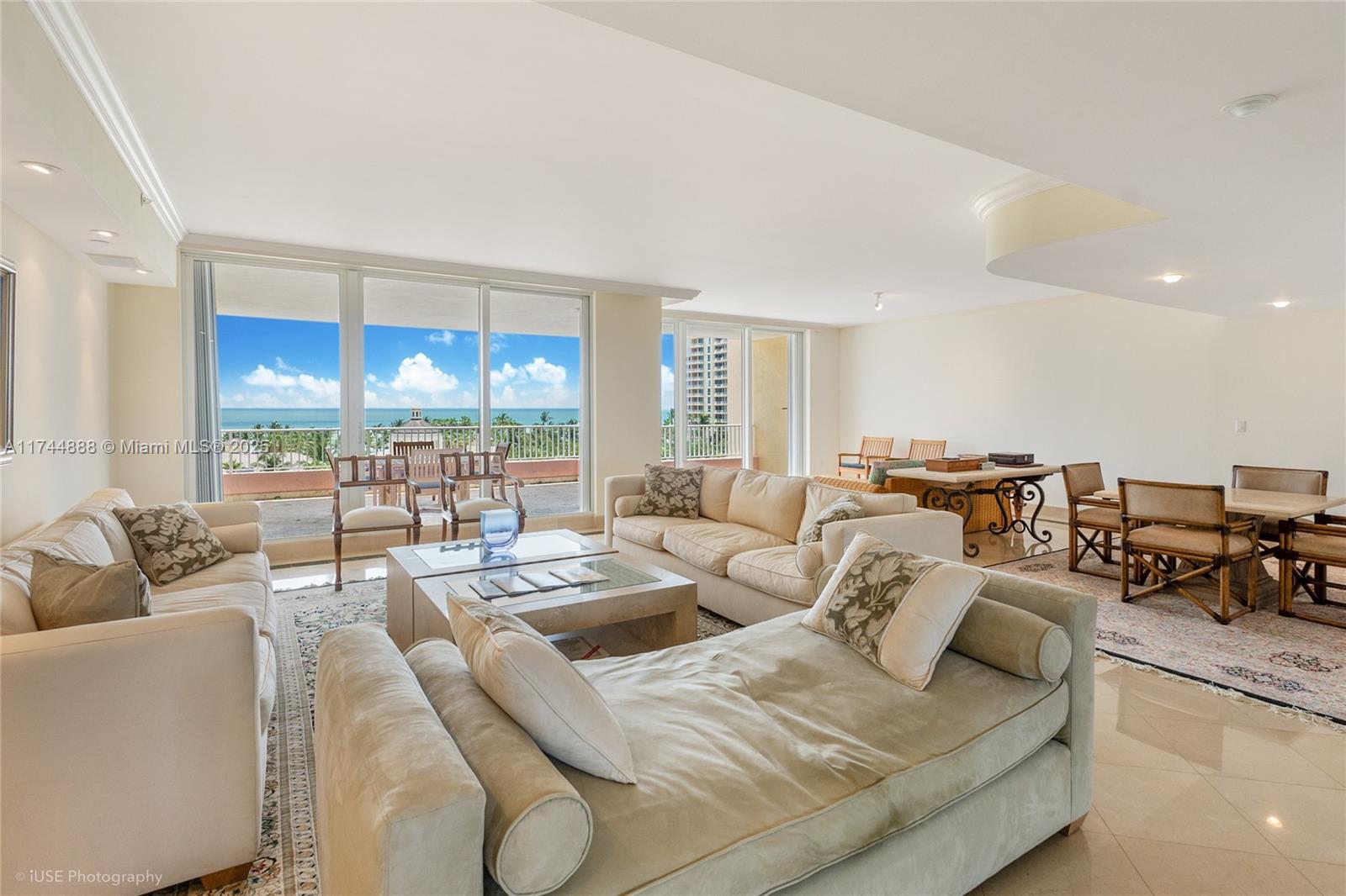 A spacious living room features beige sofas, a coffee table, and a balcony with ocean views — 785 Crandon Blvd, Key Biscayne FL 33149, KEY BISCAYNE, FL