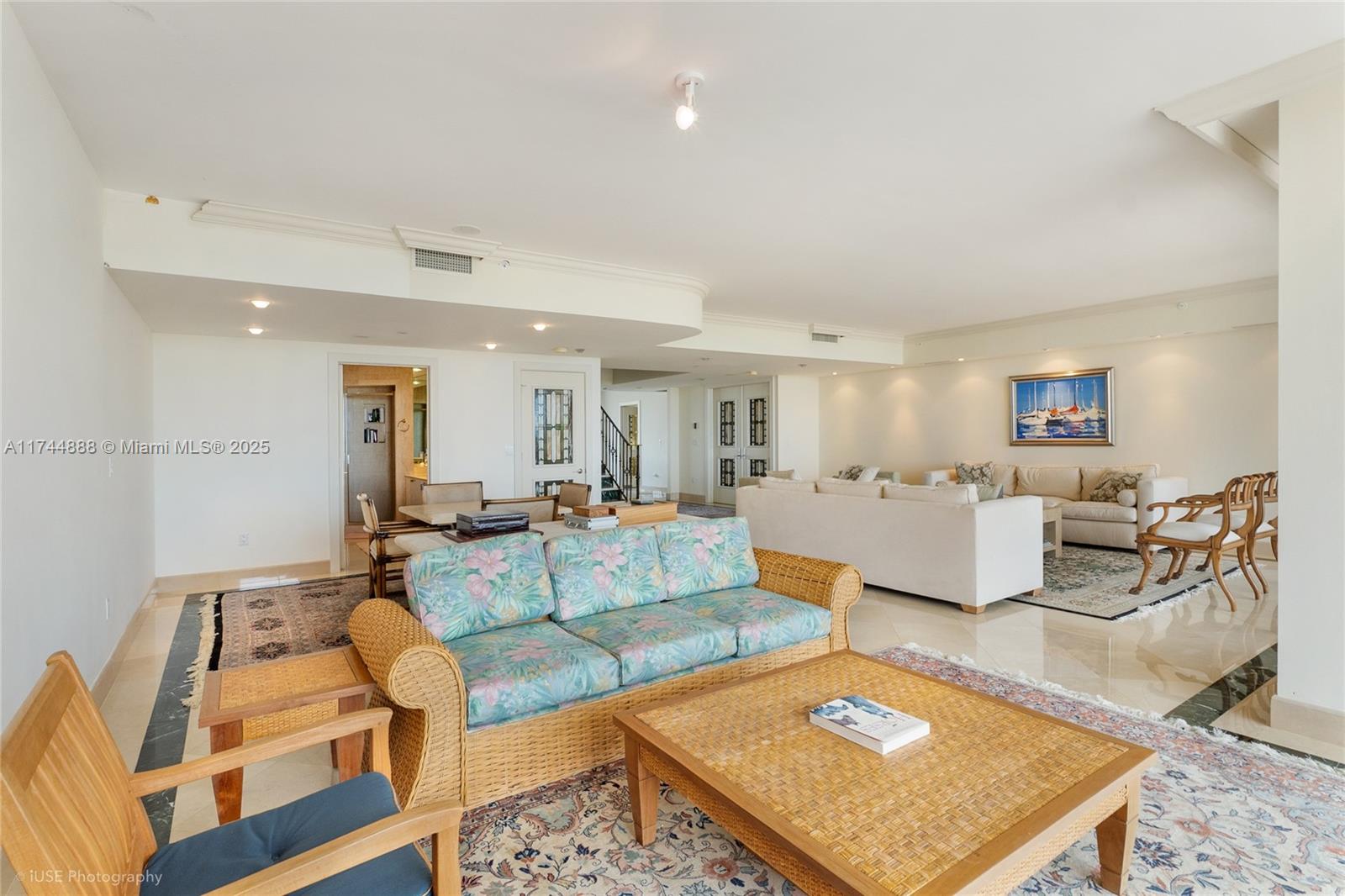 A spacious living room features tile floors, wicker furniture, and a large white sectional sofa — 785 Crandon Blvd, Key Biscayne FL 33149, KEY BISCAYNE, FL