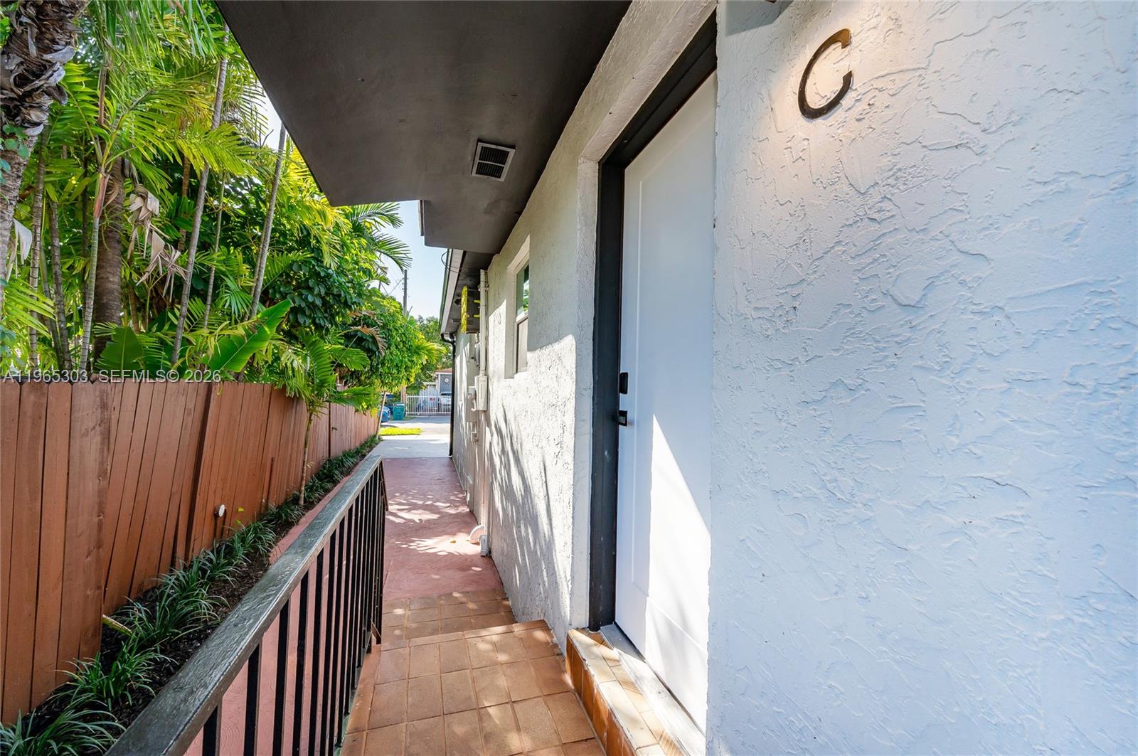 A white door marked with a C sits on a tiled walkway beside a fence — 3321 NW 19th Ter # C, Miami FL 33125, MIAMI, FL