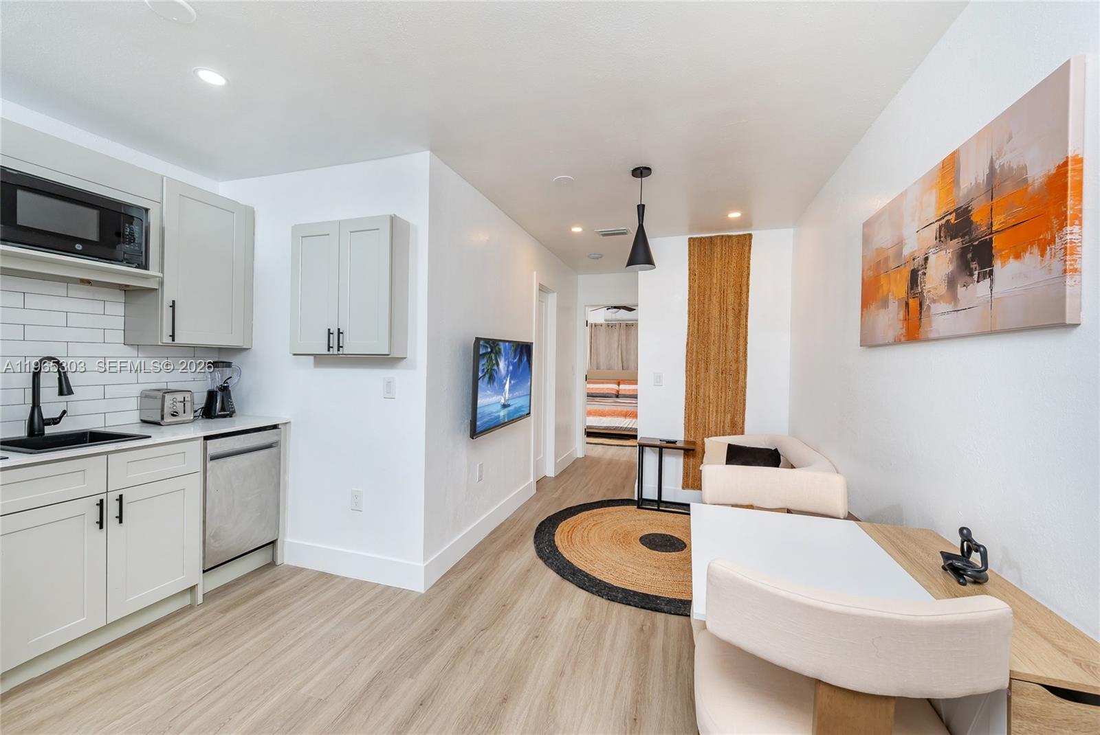 This kitchen and living area features light cabinetry, a round rug, and a dining table — 3321 NW 19th Ter # C, Miami FL 33125, MIAMI, FL