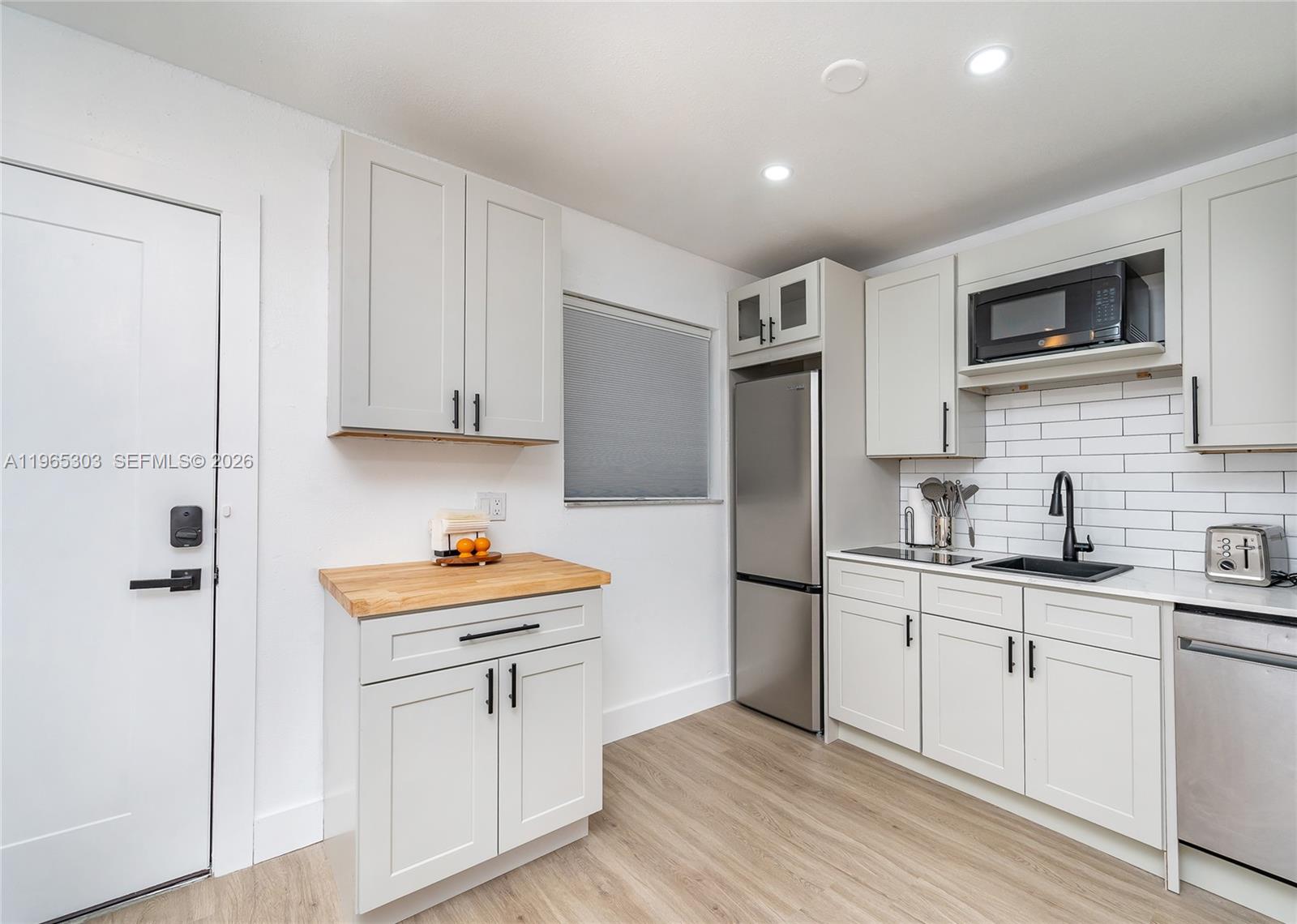 A kitchen features light gray cabinets, stainless steel appliances, a butcher block counter, and subway tile — 3321 NW 19th Ter # C, Miami FL 33125, MIAMI, FL