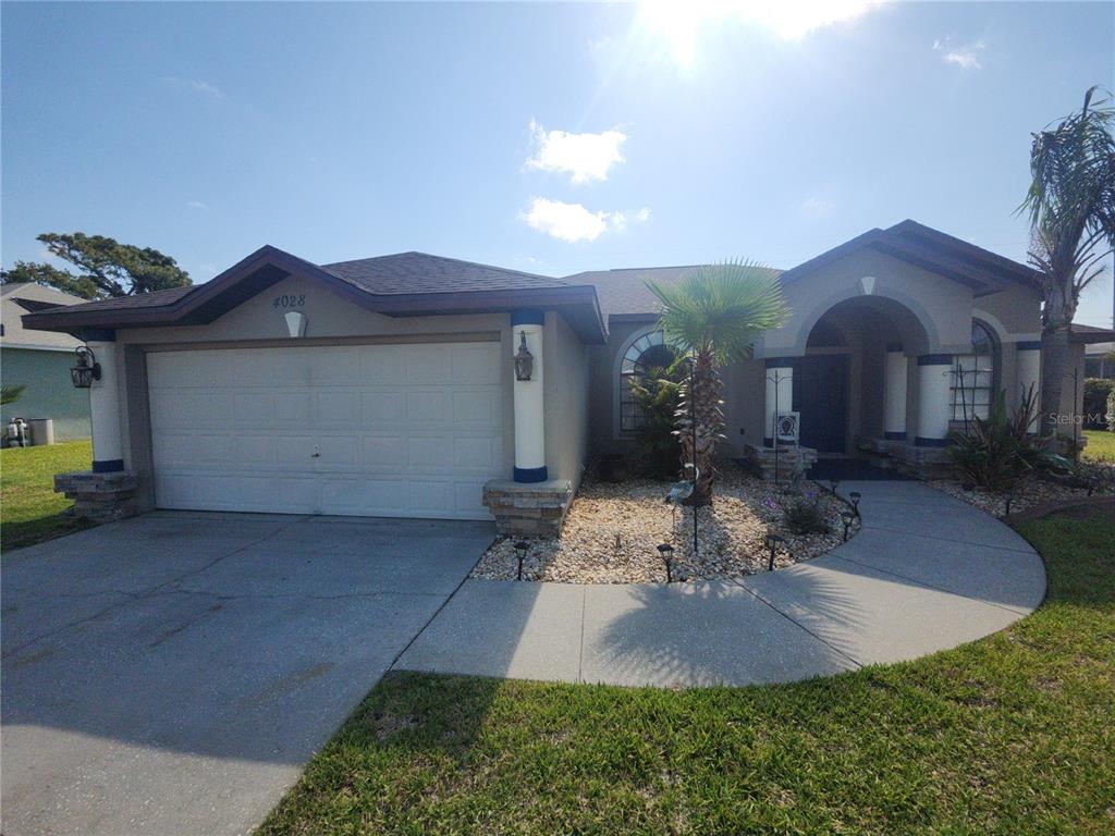 A single-story house with a two-car garage, stone-accented columns, and a paved walkway — 4028 BRECKLAND COURT, SPRING HILL, FL