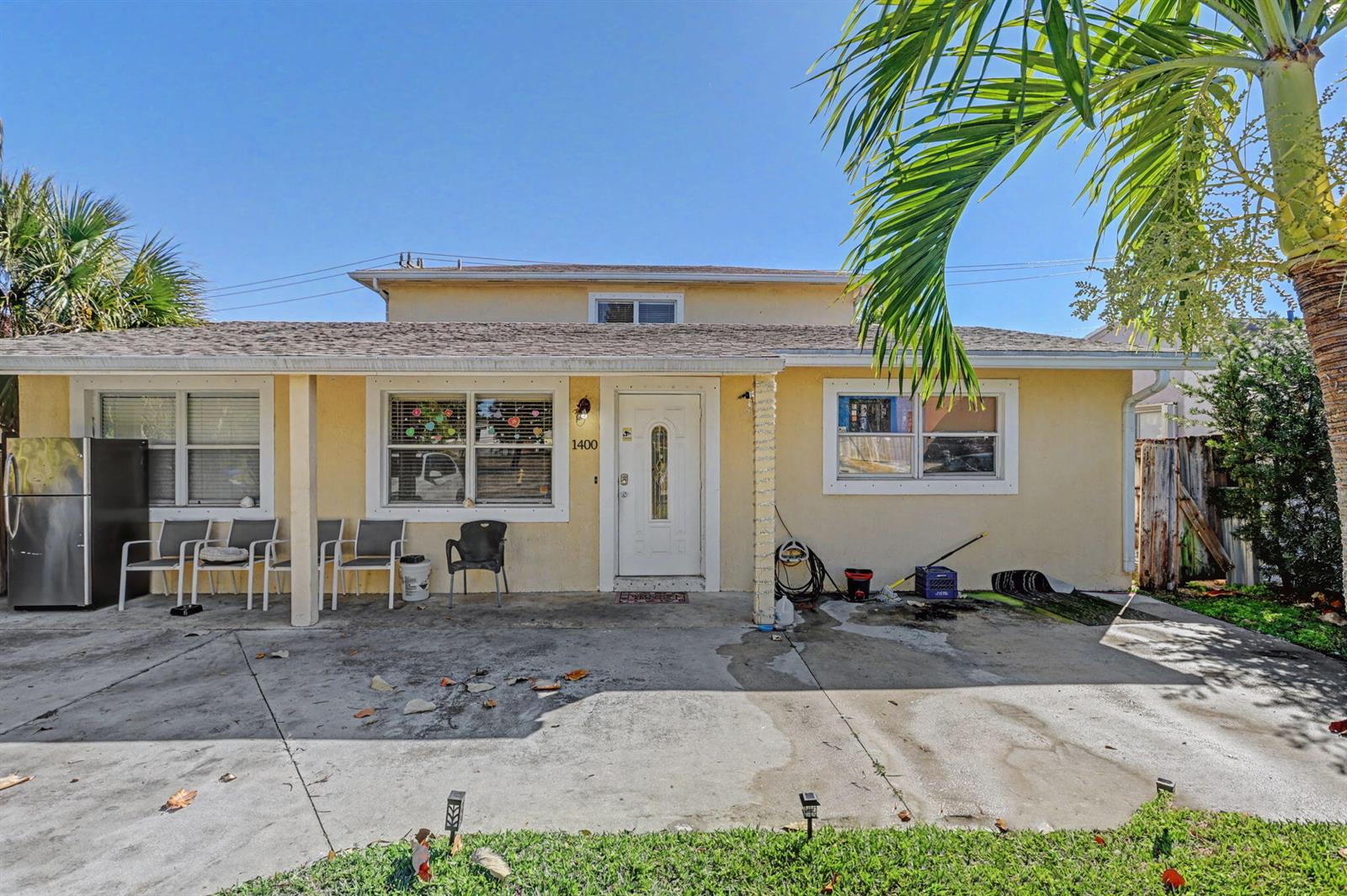 A single-story yellow house with a concrete driveway, a front porch, and a white door — 1400 Cardinal Lane, Lantana FL 33462, LANTANA, FL