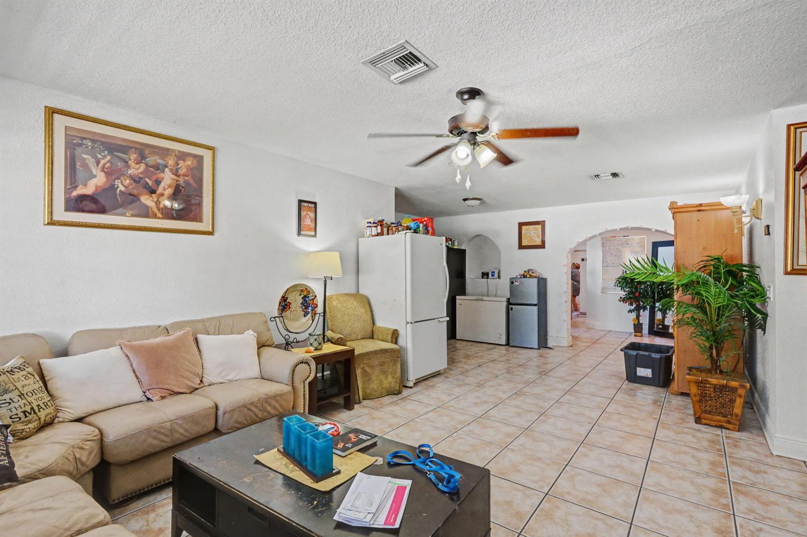 A living room features beige tile flooring, a tan sofa, a ceiling fan, and appliances — 1400 Cardinal Lane, Lantana FL 33462, LANTANA, FL