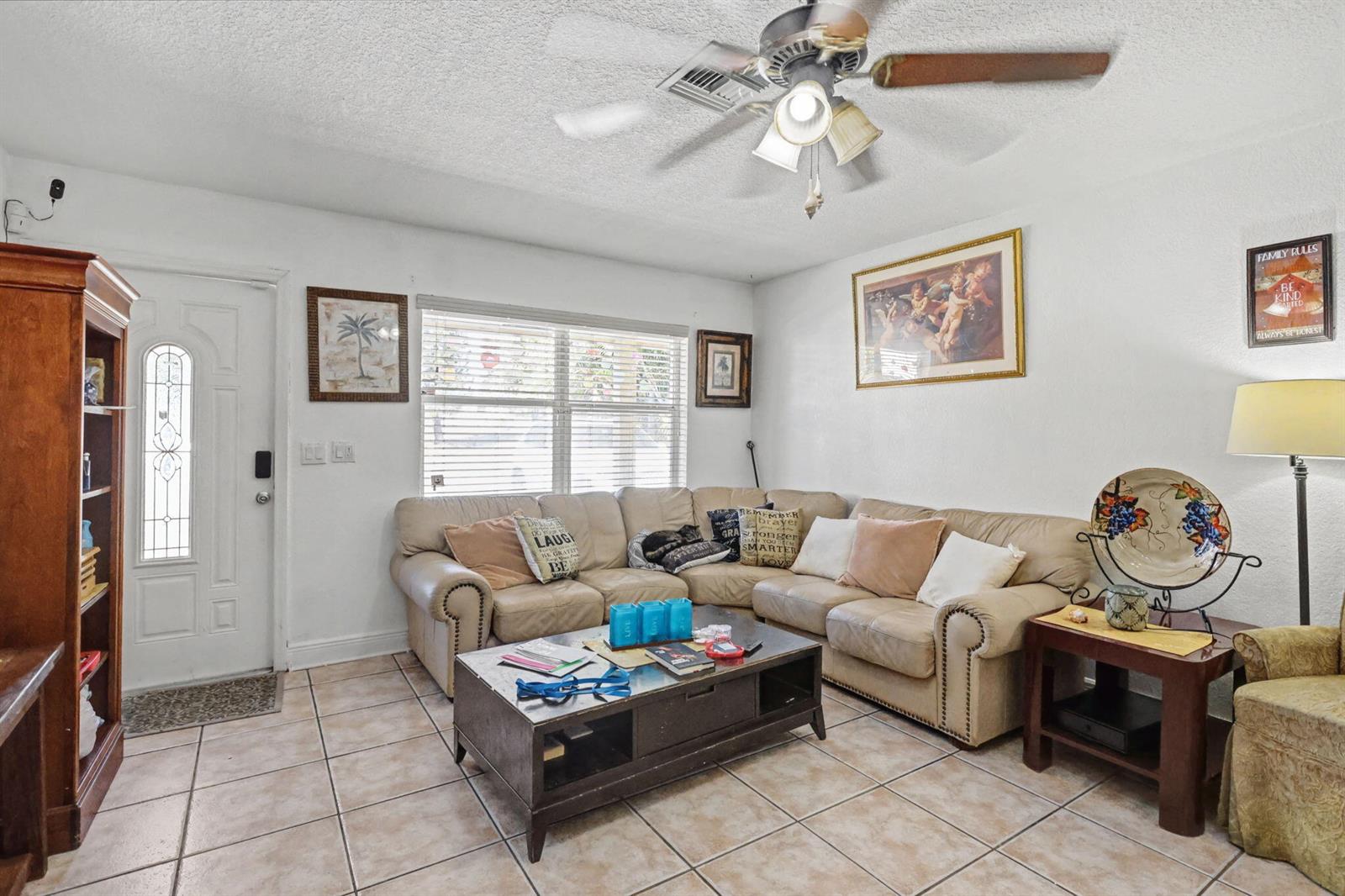 A living room features a beige sectional sofa, a coffee table, and tile flooring — 1400 Cardinal Lane, Lantana FL 33462, LANTANA, FL