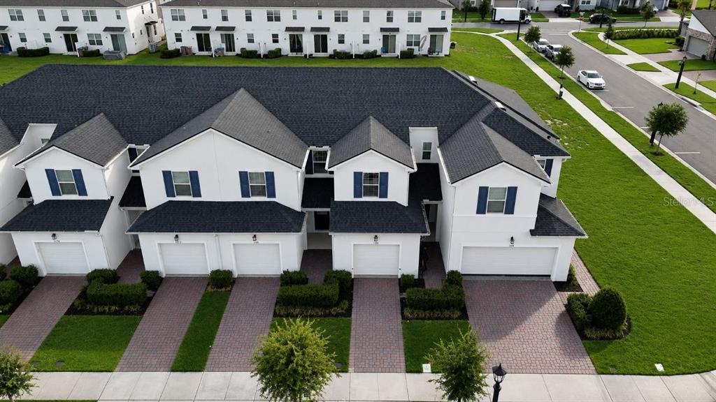 An aerial view of a row of white townhomes with dark roofs and paved driveways — 1190 SEASIDE MIST TRAIL, KISSIMMEE, FL